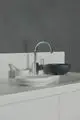 Küchenbereich mit eleganter Chrom-Armatur von Ideal Standard, weißer Spüle, schwarz gefärbtem Schalenbehälter und mehreren weißen Tellern auf der Arbeitsplatte.